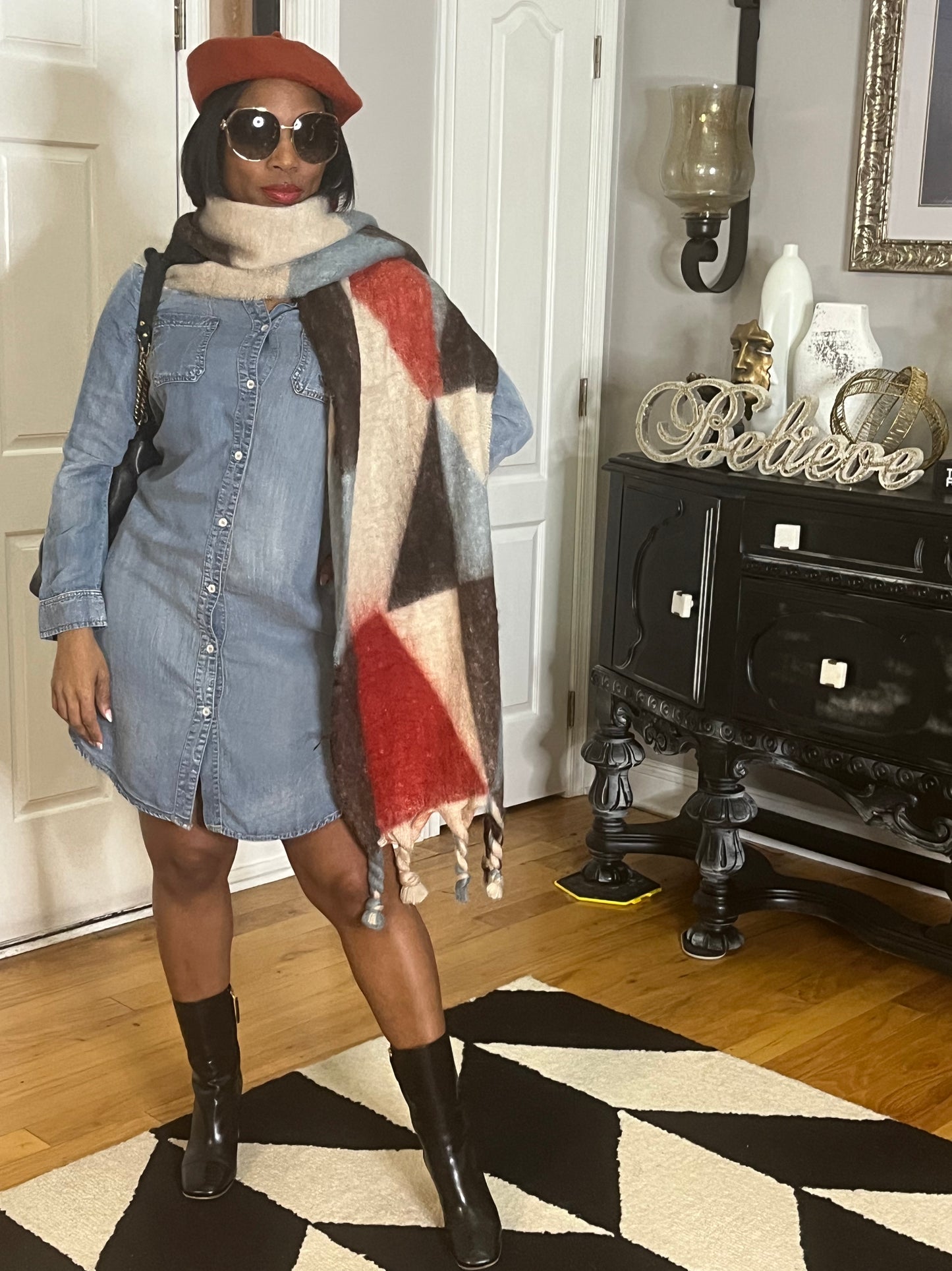 Woman standing in home with denim dress, red beret and patterned scarf