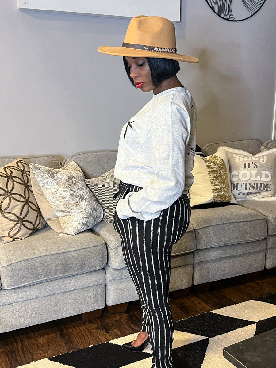 Woman wearing graphic tee, tan hat, and black and white striped pants