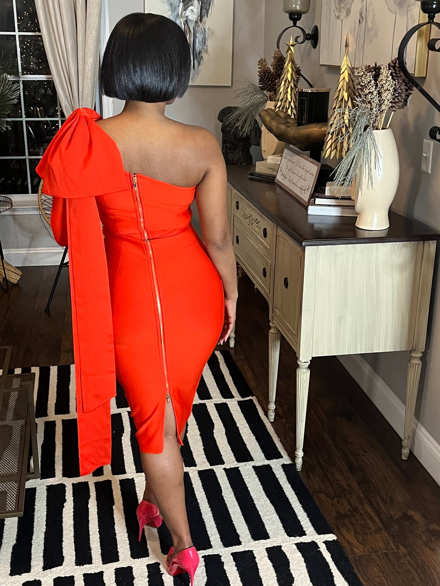 Woman modeling red dress with large bow on one shoulder