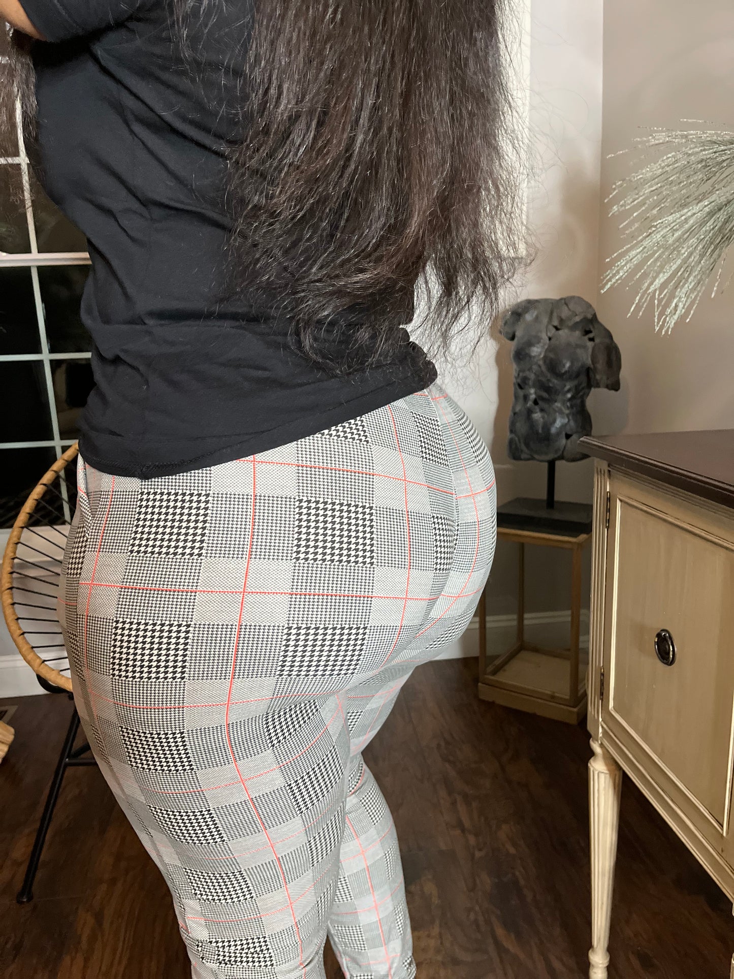 Woman modeling black top with fitted black, white, and red patterned pants