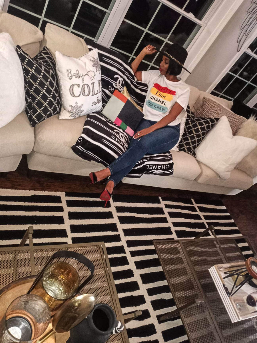 Woman sitting on couch modeling skinny jeans and tee shirt reading "Gucci, Dior, Chanel, Louis Vuitton"