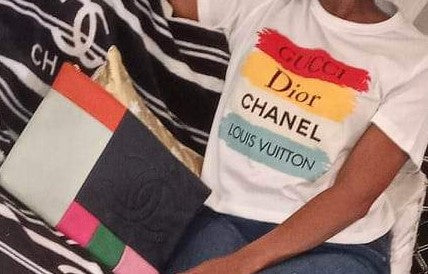 Closeup of woman wearing graphic tee that reads "Gucci Dior Chanel Louis Vuitton"