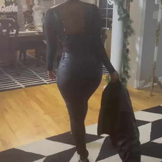 Woman walking while modeling all black outfit including fitted pants and top with a jacket