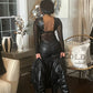 Woman modeling fitted sheer top with back cutout along with black jacket and pants